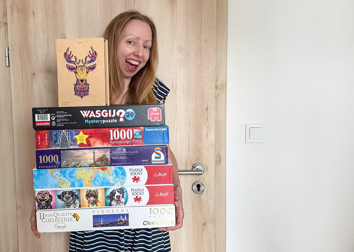 Veronika holding a stack of jigsaw puzzles reviewed in the past year